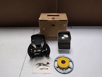 Vintage Optina film splicer, film viewer with yellow film spool, original manual, and original cardboard box arranged on table.
