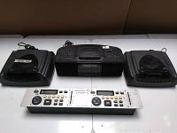 Overview photo of two black stereo speakers on either side of a black cassette player/recorder device, with American DJ DCP-5000 controller placed in front