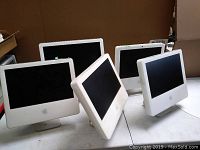 Five Apple iMac all-in-one computers front view showing white plastic bezels and black screens. Slightly angled with visible Apple logo below the center of each screen.