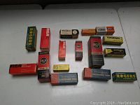 Photo of vintage electronic tubes in their original cardboard boxes from multiple brands placed on a white surface.
