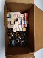 Box containing assorted vintage vacuum tubes, some boxed and some loose at bottom.