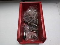 Red plastic container holding multiple vintage electronic tubes in plastic bags.