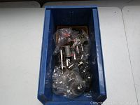 Blue plastic bin containing various vintage electronic vacuum tubes, some individually wrapped in plastic bags.