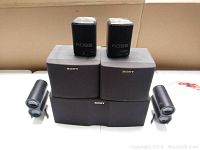 Five black speakers: two Koss speakers on top of three gray/black Sony speakers arranged on white surface.