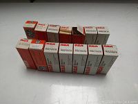 Eleven vintage vacuum tubes in original boxes arranged in a row on a surface, predominantly RCA brand tubes model 6BG1/12AX7A, some 6BQ7/12AT7A, and one GE tube box.