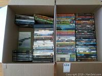 Two cardboard boxes filled with a mix of DVD cases showing spines and covers, including movies, children’s DVDs, and instructional DVDs.