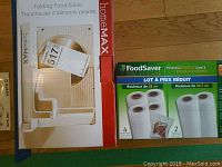 Photo of HomeMax folding food slicer box next to FoodSaver vacuum sealing rolls box on floor