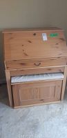 Front view of pine secretary desk with bench nested beneath it.
