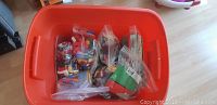 Orange plastic tub filled with assorted LEGO pieces including bags of bricks, window kits, and two building base plates.