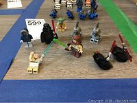 Photo of LEGO Star Wars miniatures including Yoda, Darth Vader, Jedi, and battle droids arranged on flat surface.