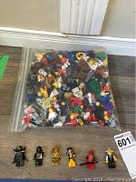 Large resealable bag of LEGO minifigure parts including heads, torsos, legs, and accessories