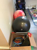Photo showing two large exercise balance balls and a box with exercise accessories including resistance ring and putty.