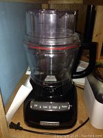 Photo showing Kitchenaid food processor base with clear plastic bowl and lid with red seal, control panel with Off, Low, High, Pulse buttons