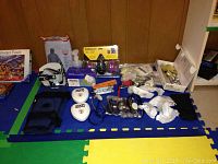 Collection of medical equipment and supplies on foam mat including knee brace, blood pressure monitor, stethoscopes, masks, syringes, and first aid items.