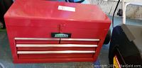 Front view of red Jobmate metal tool chest with three drawers and hinged lid, showing logo on front and metal handles.