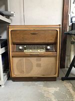 Front view of the 1950s wooden hi-boy radio cabinet with woven speaker grille and control panel.