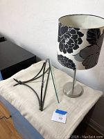 Lamp with floral shade and wall sconce laid on cloth-covered surface