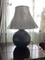 Silver lamp with round ribbed base and custom pleated shade, side view