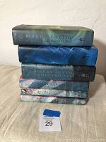 Stack of six hardcover Harry Potter books showing spines with titles and varying colors including green, blue and purple.