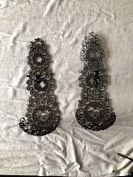 Pair of wrought iron candle sconces shown side by side on a fabric background, displaying scrollwork design and candle holders