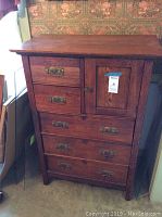 Front view of wooden bonnet chest showing 5 drawers and cabinet.