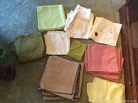 Folded assorted kitchen linens in various colors laid out on a floor.