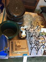 Photo showing enamel roasting pot with lid, green crockpot insert, two glass steamers with lids, metal trivets, white plastic measuring scoops, insulated lunch bag, and boxed apple peeler with stand.