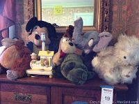 Front view of all items including three Disney plush characters and vintage wooden shoe lamp base on wooden dresser.