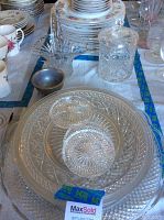 Photo of stacked glass plates, sugar bowl with lid, creamer pitcher, and small serving bowls on a table
