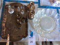 Photo showing metal serving tray with patina, clear glass deviled egg plates, silver floral salt and pepper shakers, and two sterling weighted candlestick holders