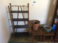 Four-tier bamboo shelving unit, two bamboo stools, and three planters (two wicker and one ceramic) grouped together on floor.
