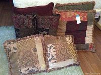 Six assorted throw pillows arranged on sitting surface showing variety of colors, patterns, and shapes.