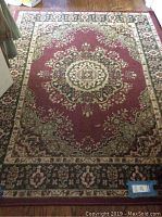 Full view of maroon and beige small area rug with floral medallion design.