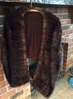 Dark brown mink fur stole hanging with visible brown fabric lining embroidered with initials 'MFJ'.