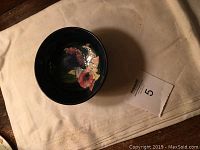 Top view showing floral pattern inside bowl with dark blue background and approximately 5 inches diameter.