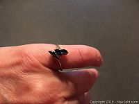 Photo of ring on finger showing sapphire and diamond cluster setting.