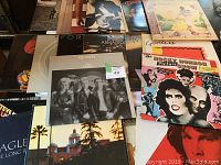 Multiple vinyl LP covers arranged showing front covers of Queen – The Game, Prism – Armageddon, The Rocky Horror Picture Show, Eagles Hotel California and others