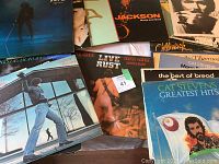 Overhead view of vinyl albums spread on table showing visible artists including Joe Jackson, Cat Stevens, Men at Work, Pink Floyd.