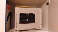 Front view of the closed white safe showing its compact size and black lock system.