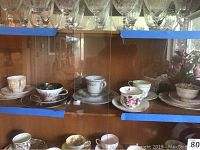 Photo of six tea cups and saucers on wooden shelves showing a variety of floral patterns and gilt trims