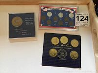 World War II Lincoln Penny Set with visible slots for 1943, 1944, and 1945 pennies, United States Bicentennial Anniversary coin in protective case, and a set of five presidential quarters on display.