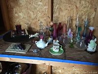 Shelving with variety of glass vases, candleholders, small containers, stemware, and decorative items in multiple colors and sizes