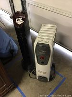 Photo showing both a white Delonghi Safe Heat oil heater and a black Sharper Image Ionic Breeze GP air purifier side by side on a garage floor.
