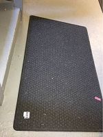 Single dark utility rug laid on floor showing textured woven pattern and size.