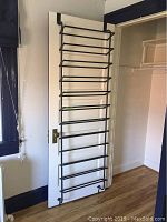 Full view of black metal hanging shoe rack hanging on door, showing size and construction