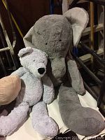 Gray elephant plush and smaller gray bear plush together showing size comparison and detail.