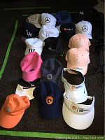 Image top view of 17 baseball caps of various colors and brands, showing logos and designs.