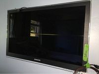 Front view of Samsung 32" flat screen TV mounted on wall, powered off, showing model and bezel details.