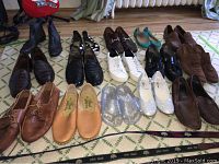 Various men and women shoes spread on rug, different styles including dress shoes, boots, flats.