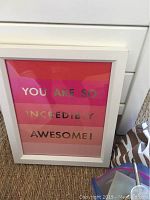 Framed wall art with motivational message in pink and red blocks with white frame.